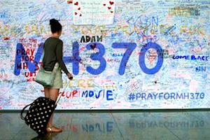 Picture: A Passenger walks past a banner filled with signatures and well-wishes for the missing passengers and crew of Malaysia Airlines MH370 at Kuala Lumpur International Airport (courtesy E&T Magazine)