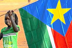 Picture: A young girl holds the South Sudan flag courtesy Timothy McKulka/USAID/Wikimedia Commons.